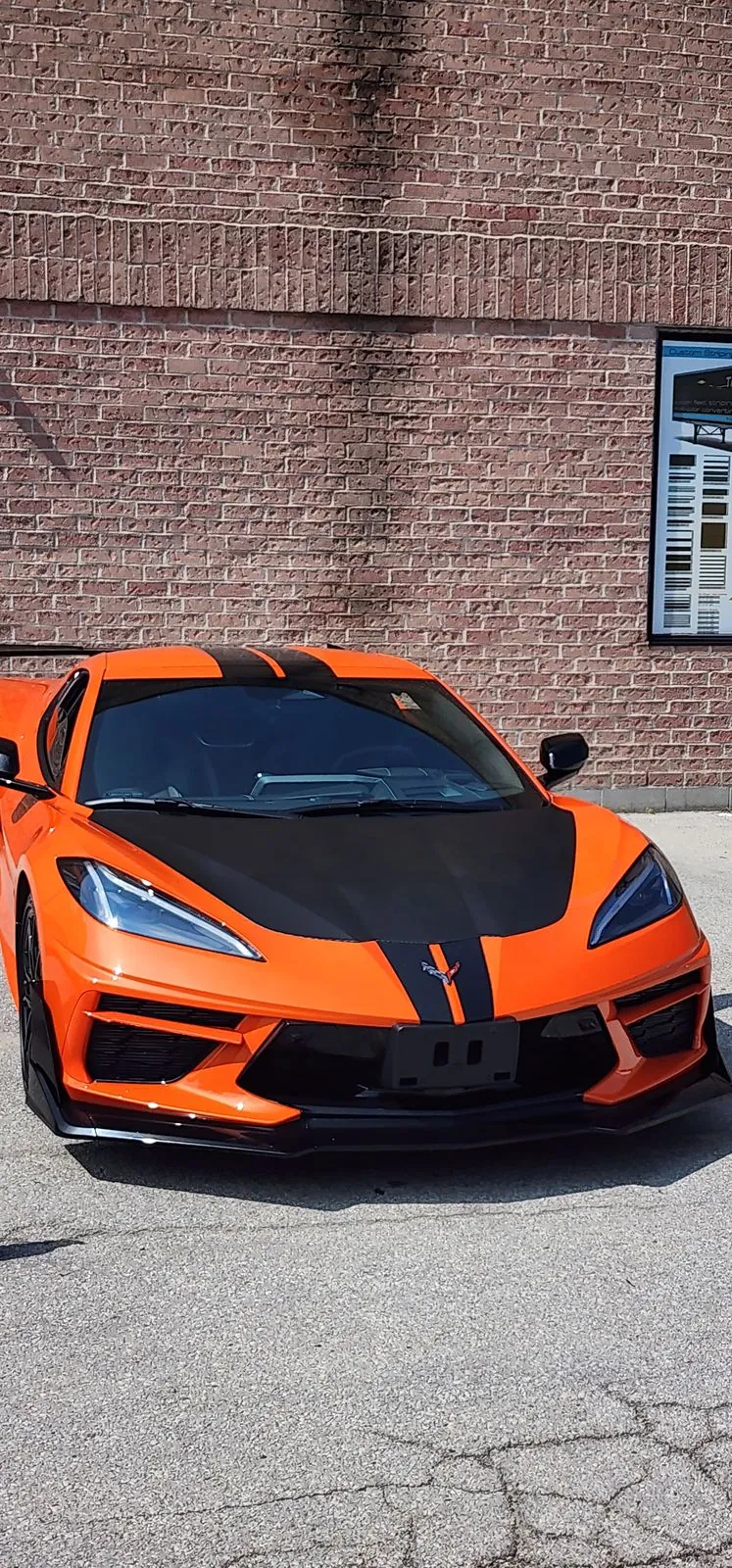 Orange Corvette C8 with black hood wrap and racing stripes